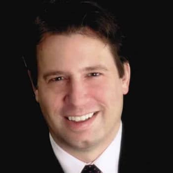 a man in a suit and tie smiling at the camera.