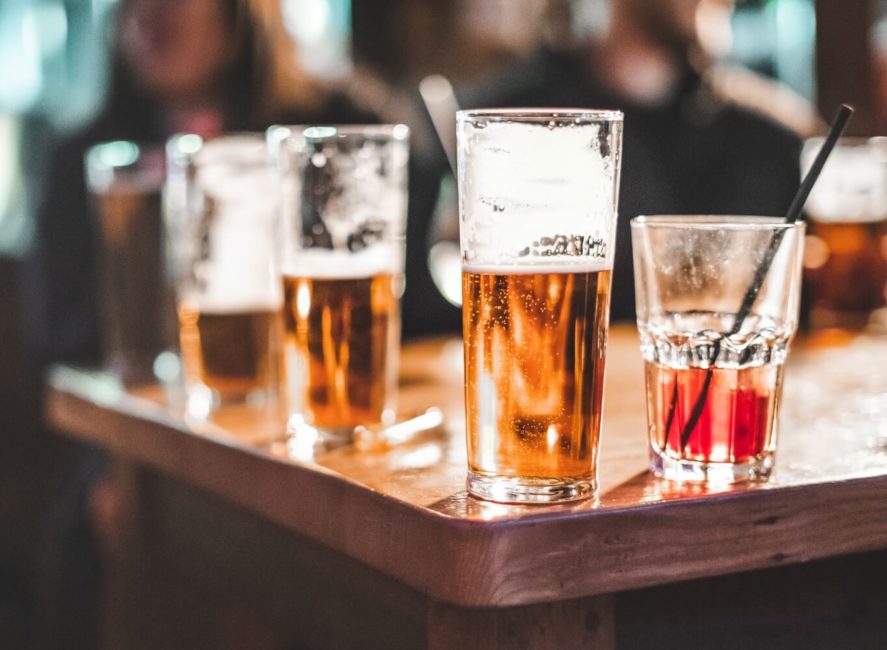 a wooden table topped with glasses of beer.