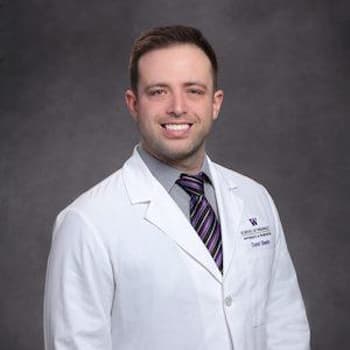 a male in a white lab coat and tie.