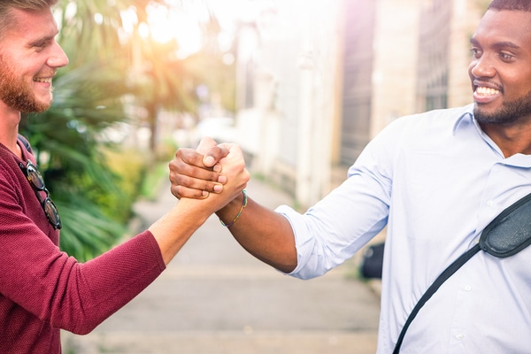 a couple of men holding hands on a street.