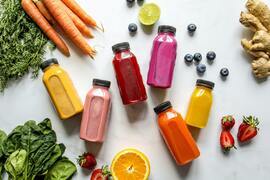 a table topped with fruits and vegetables next to juice.