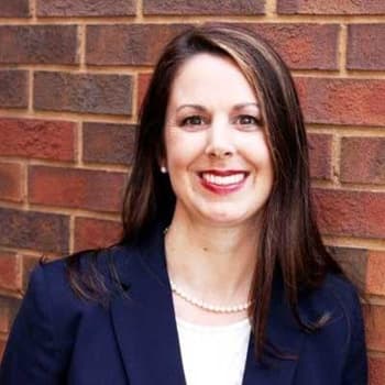 a woman standing in front of a brick wall.