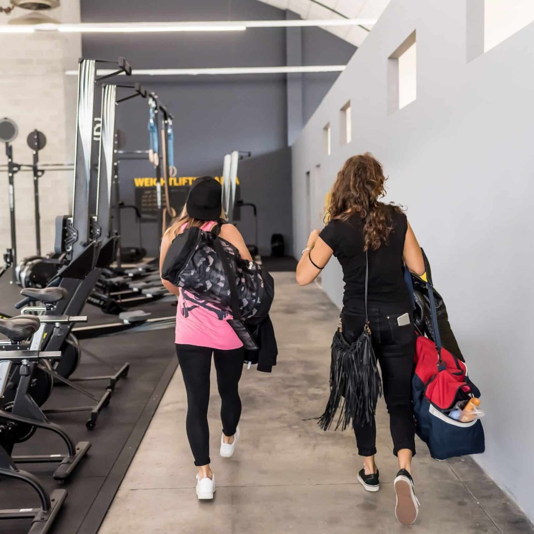 two-women-holding-gym-bag-walking-indoors-2023-11-27-05-01-28-utc-min