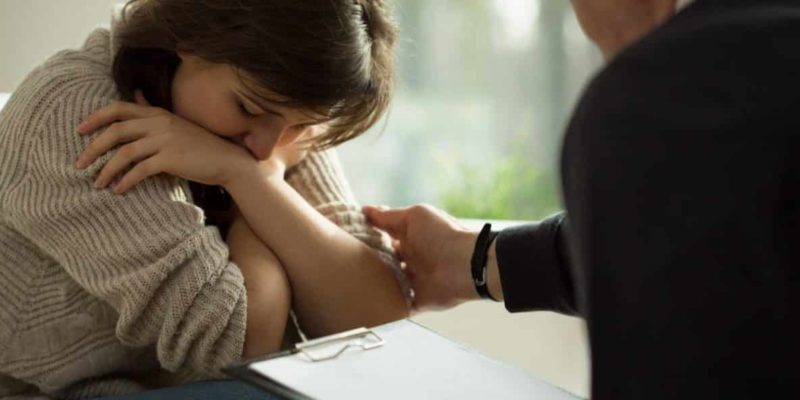 a woman holding her head while sitting next to a man.