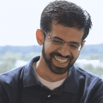 a man with a beard and glasses smiling.