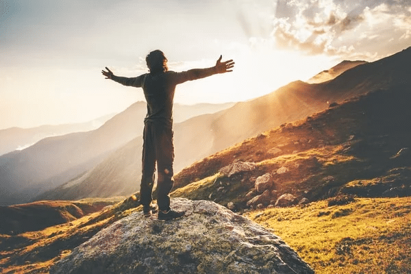 a man standing on top of a rock in the mountains.