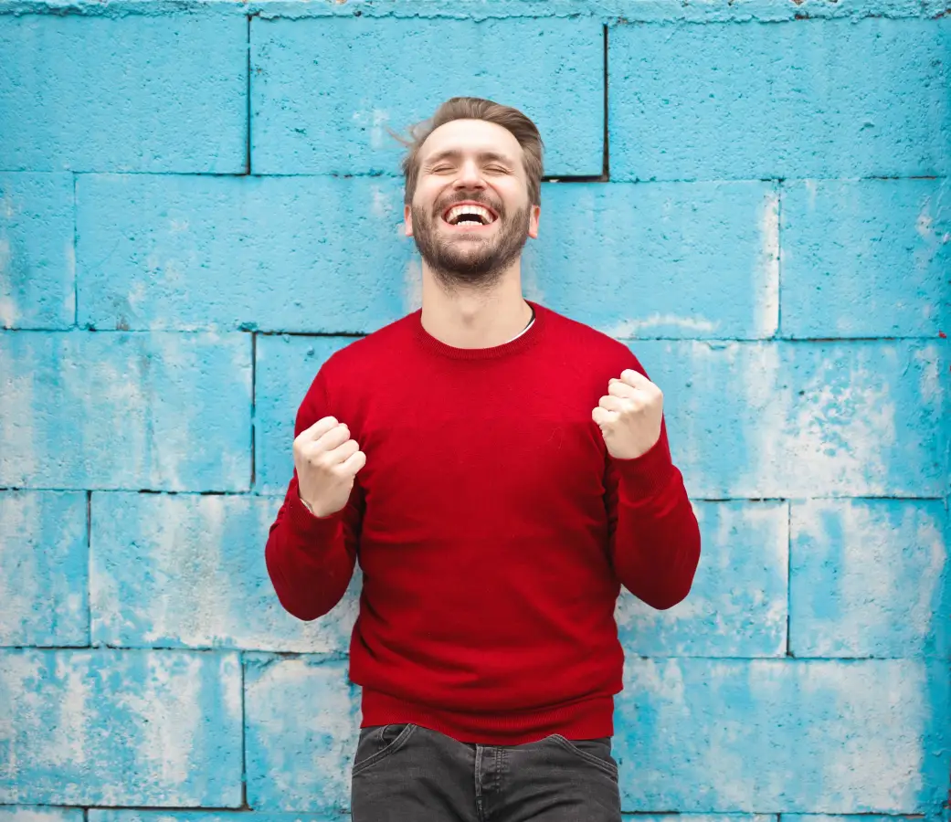 Man happy against blue brick wall