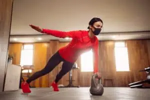 Sport Girl In Mask from Coronavirus doing Kettlebells Planking